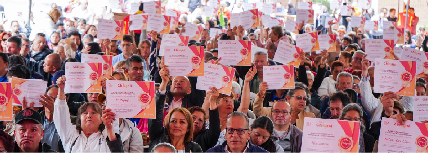 Ciudadanos y organizaciones comunitarias levantan certificados durante la entrega simbólica de incentivos del Fondo Chikaná 2025, evento de Participación Bogotá que fortalece la acción comunal y el liderazgo ciudadano.
