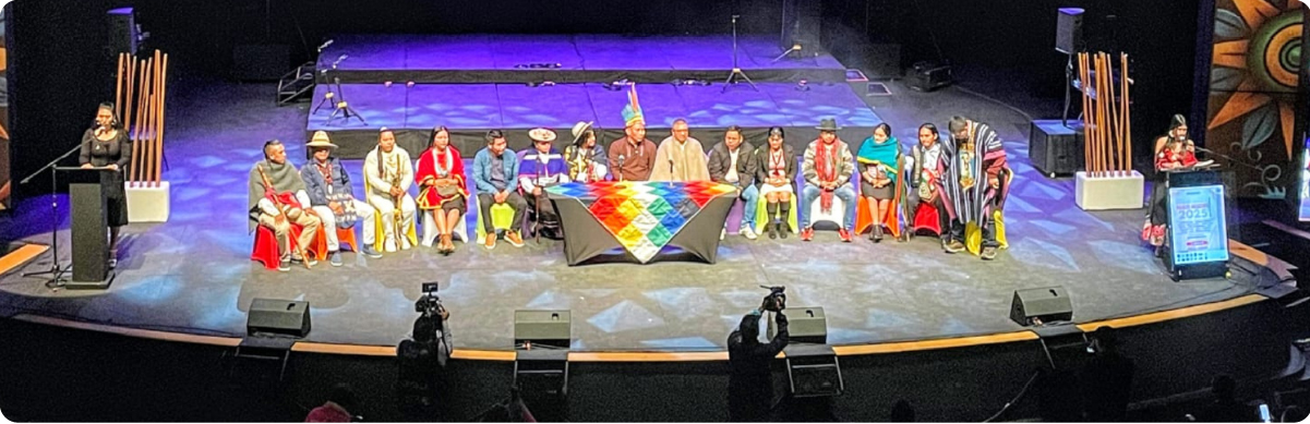 Representantes de pueblos indígenas participan en un encuentro cultural y comunitario en un auditorio de Bogotá.