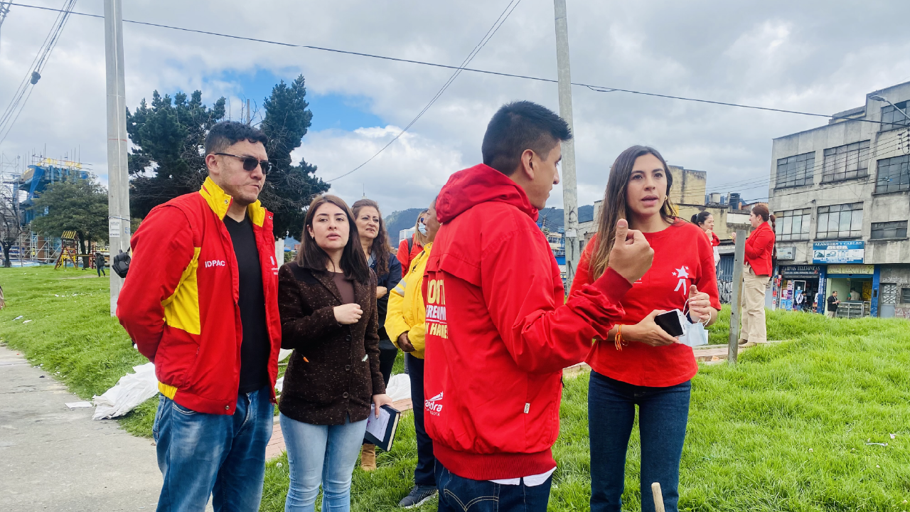 Grupo de funcionarios del IDPAC y la Alcaldía Local dialogando durante una visita territorial en el barrio La Fragüita, en un espacio verde donde realizan diagnóstico y trabajo comunitario.