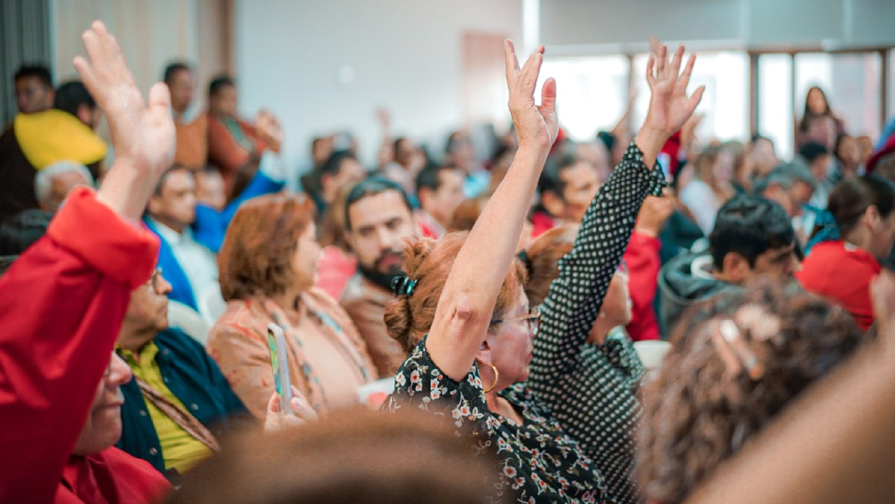 Ciudadanos participan en una jornada de formación levantando la mano durante cursos de la Escuela de la Participación en Bogotá