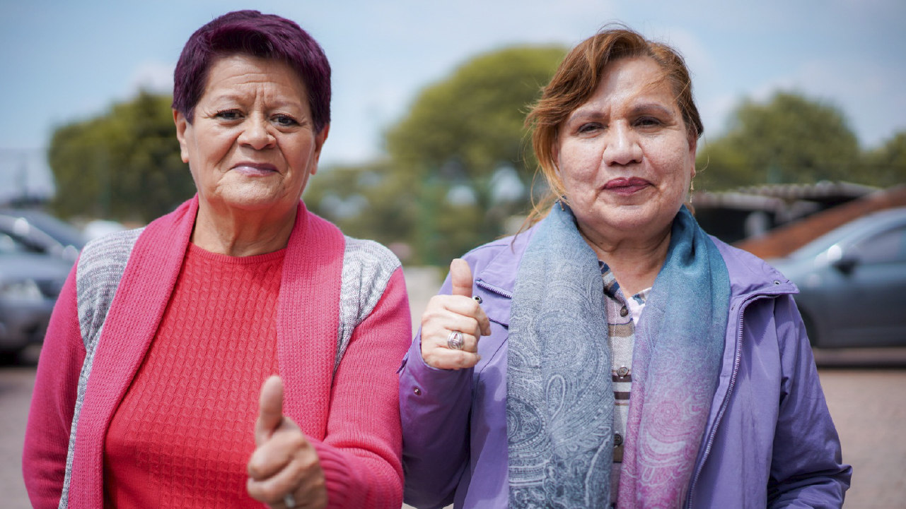 Dos mujeres adultas en espacio público de Bogotá levantan el pulgar como señal de apoyo durante el inicio de las votaciones para los Consejos de Vendedoras y Vendedores Informales.