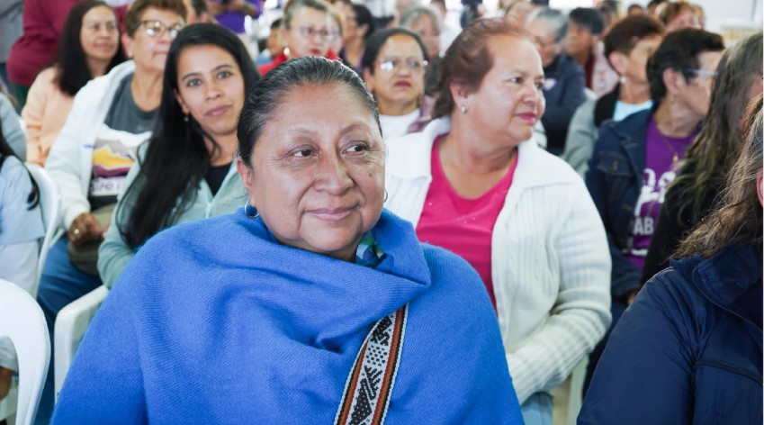 Mujer adulta envuelta en un chal azul participa en un encuentro comunitario en Bogotá, rodeada de otras asistentes