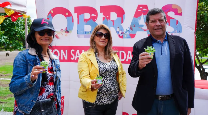 Personas de la comunidad participan en la entrega simbólica de plantas durante una jornada de obras comunitarias en Bogotá.