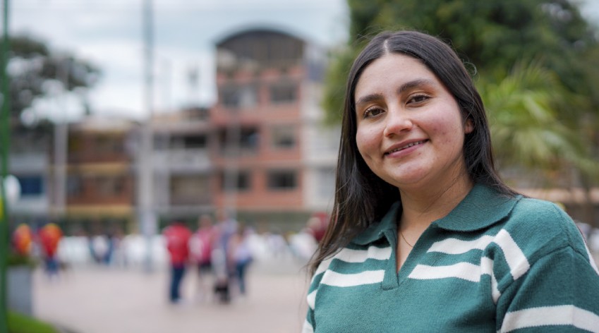 Mujer joven sonriente, potencial votante, en un espacio comunitario de Bogotá, representando la participación ciudadana en la cuenta regresiva para las elecciones comunales.