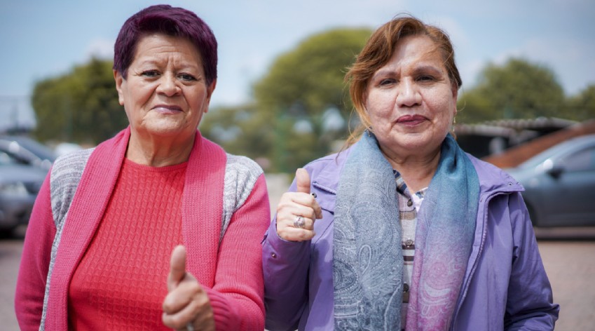 Dos mujeres adultas en espacio público de Bogotá levantan el pulgar como señal de apoyo durante el inicio de las votaciones para los Consejos de Vendedoras y Vendedores Informales.
